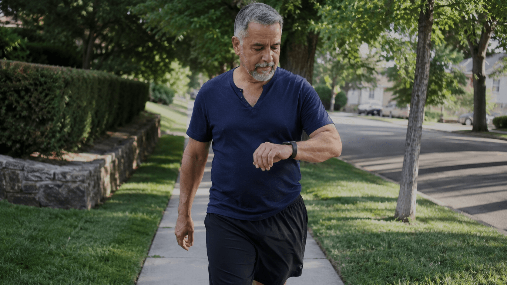 A man checking his fitness watch as he walks.